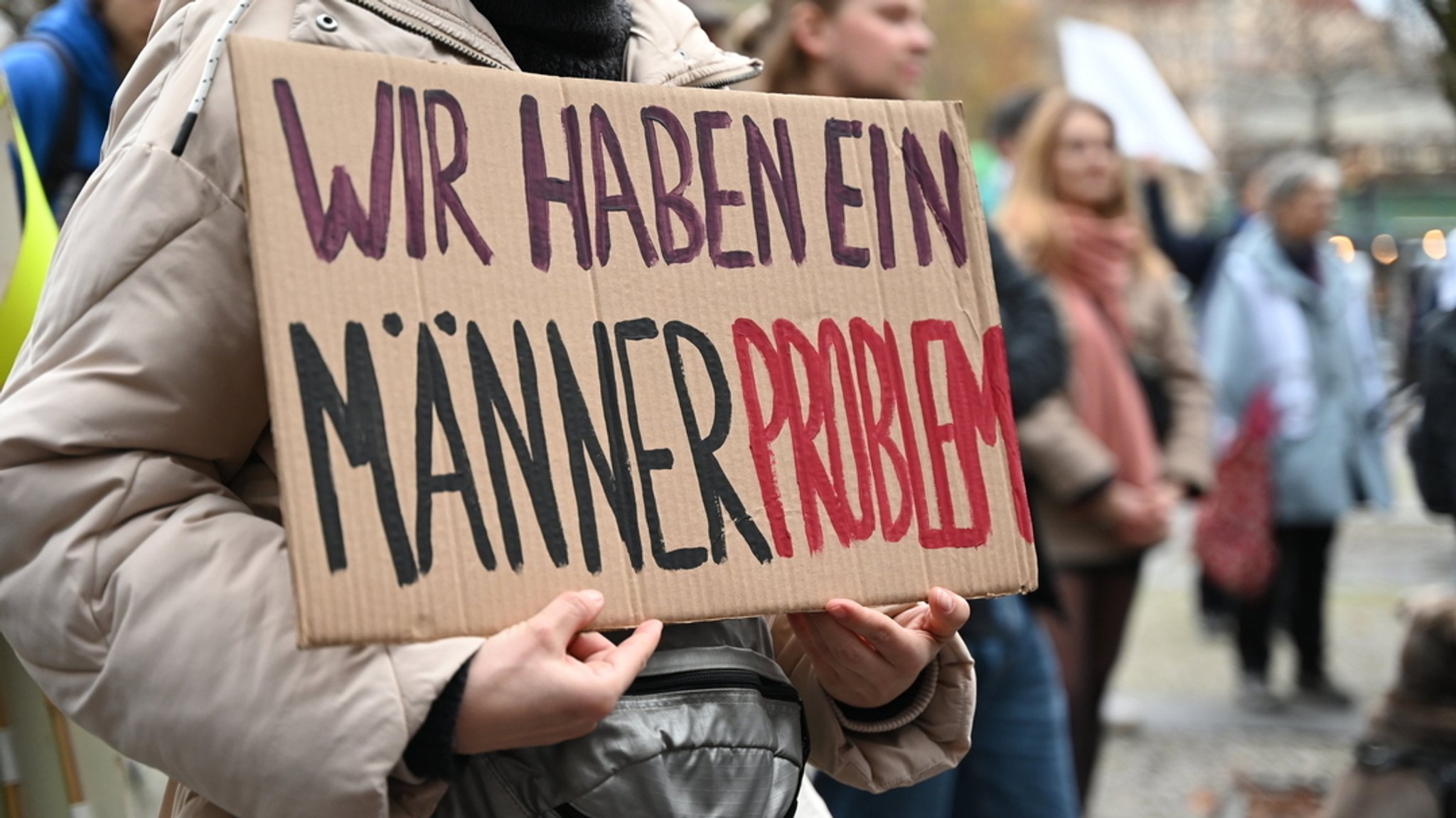 Eine Frau hält ein Schild mit der Aufschrift "Wir haben ein Männerproblem" während einer Demonstration am Internationalen Tag für die Beseitigung von Gewalt gegen Frauen.