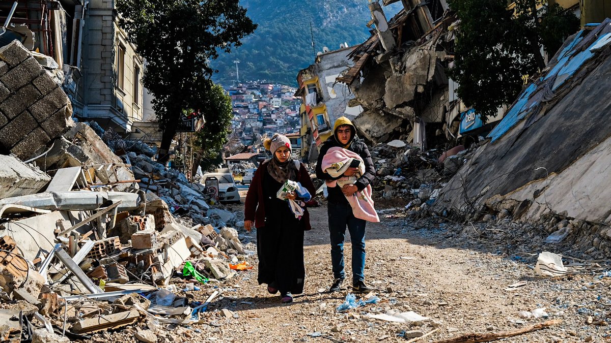Eine junge Familie nach dem Erdbeben zwischen zerstörten Häuserreihen in der türkischen Provinz Hatay (Archiv: 12.02.2023) 