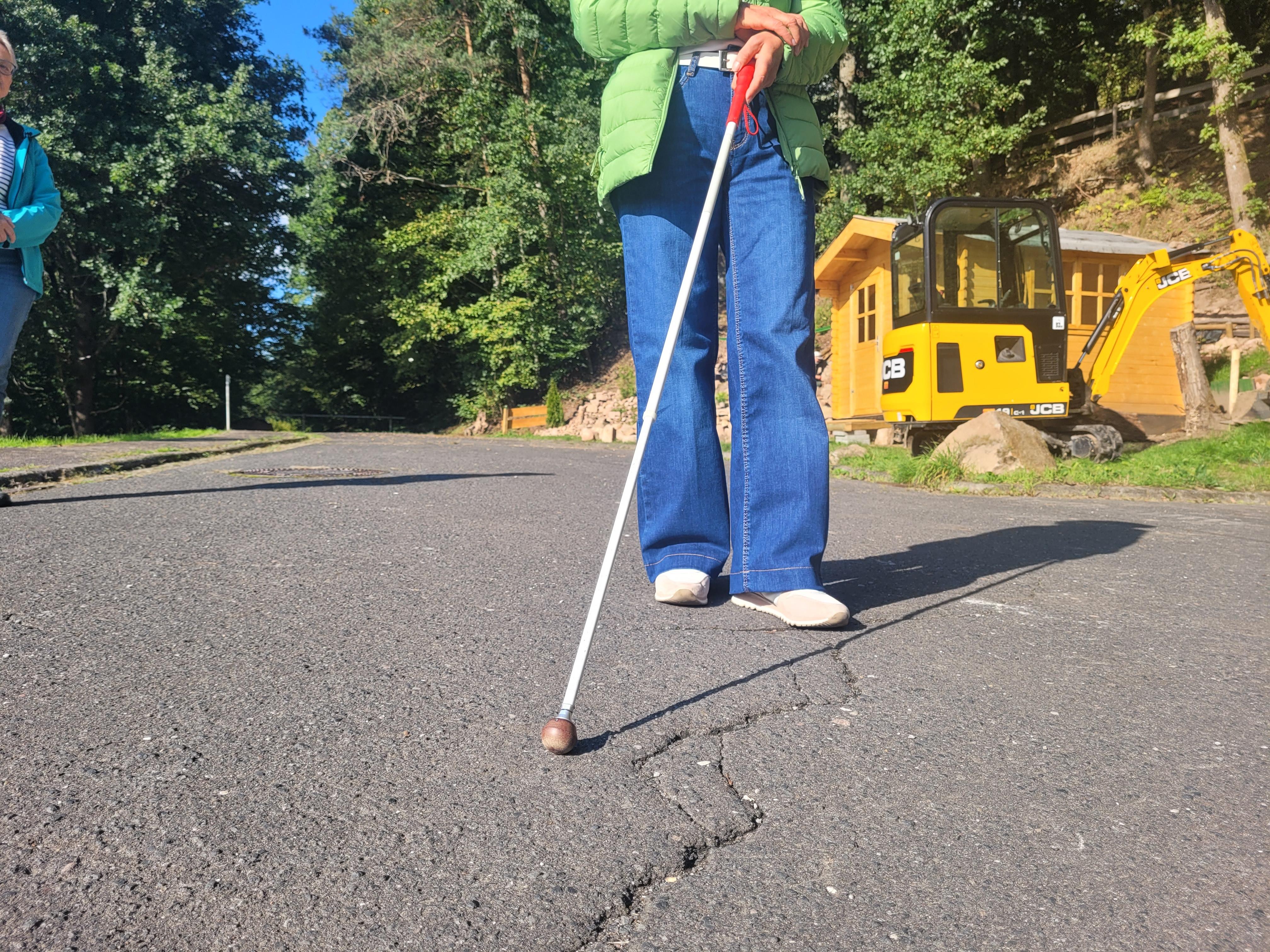 Eine Frau ertastet mit einem Blindenstock den Untergrund.