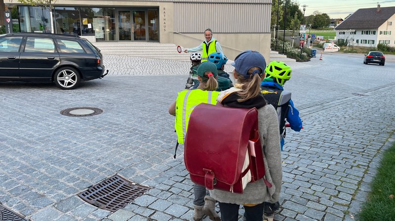 Kinder werden von einem Schulweghelfer über die Straße geleitet. | Bild: BR/Katharina Reichart Kinder werden von einem Schulweghelfer über die Straße geleitet.