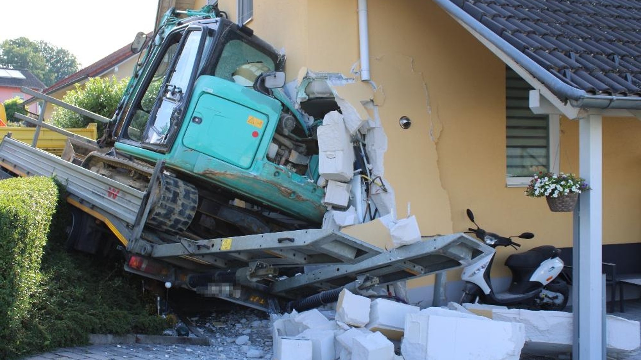 Anhänger mit Bagger stürzt in ein Haus