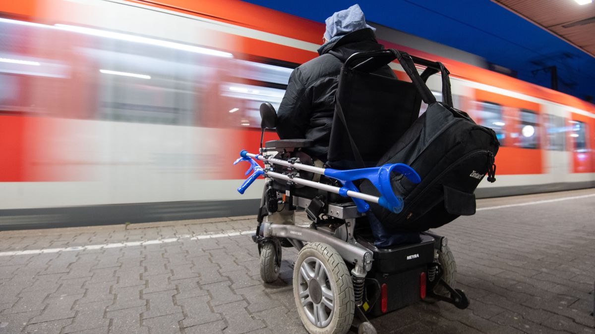 Mann mit elektrischem Rollstuhl auf einem Bahnsteig