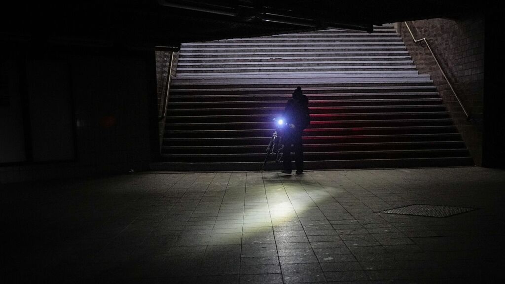 03.01.2026, Berlin: Ein Mann geht mit seinem Fahrrad durch den Bahnhof Wannsee nach einem Stromausfall. Nach einem Brand an einer Kabelbrücke am Kraftwerk Lichterfelde kommt es durch den Stromausfall im Südwesten von Berlin zu Beeinträchtigungen. Foto: Michael Kappeler/Dpa/dpa +++ dpa-Bildfunk +++