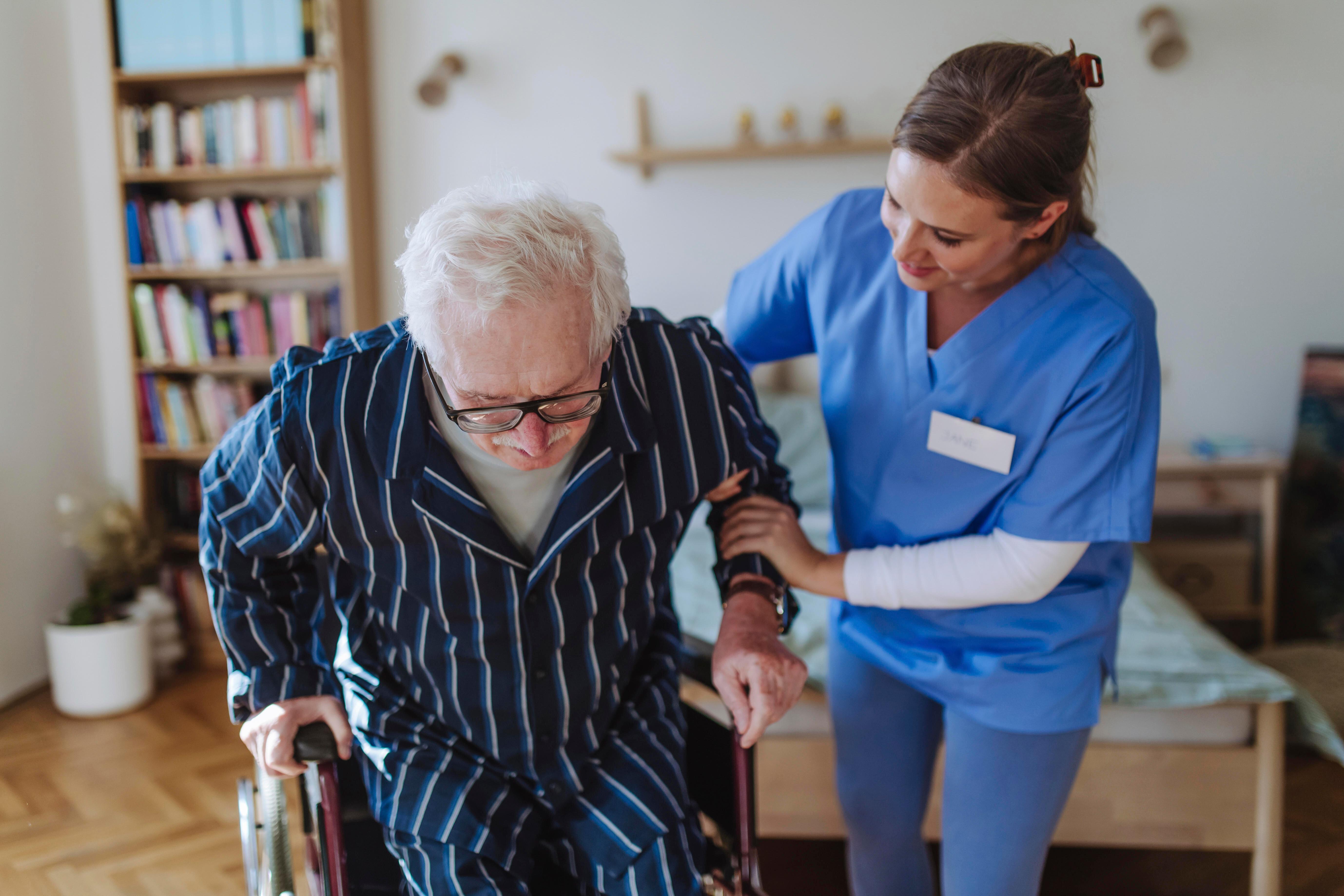 Pflegekraft stützt älteren Mann