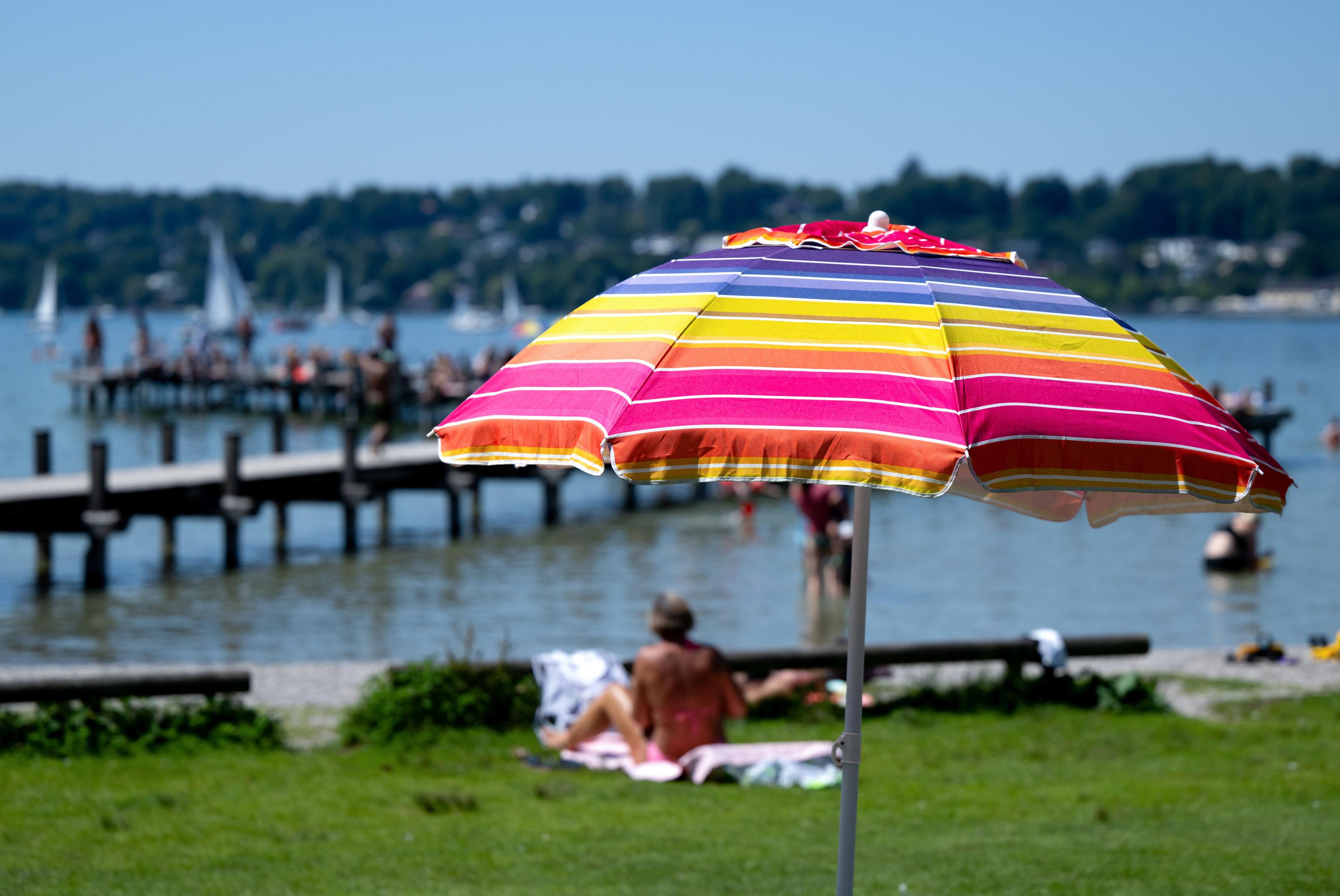 08.08.2025, Bayern, Percha: Menschen genießen das warme Wetter und den Sonnenschein auf einem Steg am Starnberger See. Foto: Sven Hoppe/dpa +++ dpa-Bildfunk +++