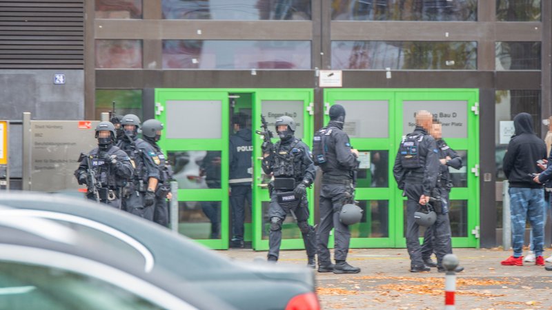 Spezialeinsatzkräfte der Polizei in Schutzmontur vor dem Eingang einer Schule.