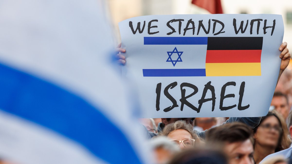 "We stand with Israel" (Wir stehen Israel bei) steht auf dem Plakat eines Teilnehmers einer Solidaritätskundgebung in Nürnberg für Israel. 