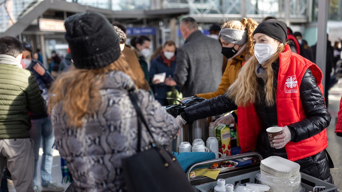 Eine Mitarbeiterin der Caritas verteilt am Münchner Hauptbahnhof an Flüchtlinge aus der Ukraine Essen und Getränke.