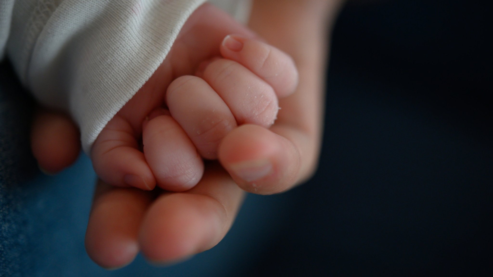 Die Hand eines Säuglings liegt in der Hand seiner Mutter (Symbolbild).