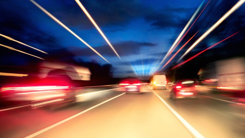 Autos auf der nächtlichen Autobahn mit Lichtspuren.