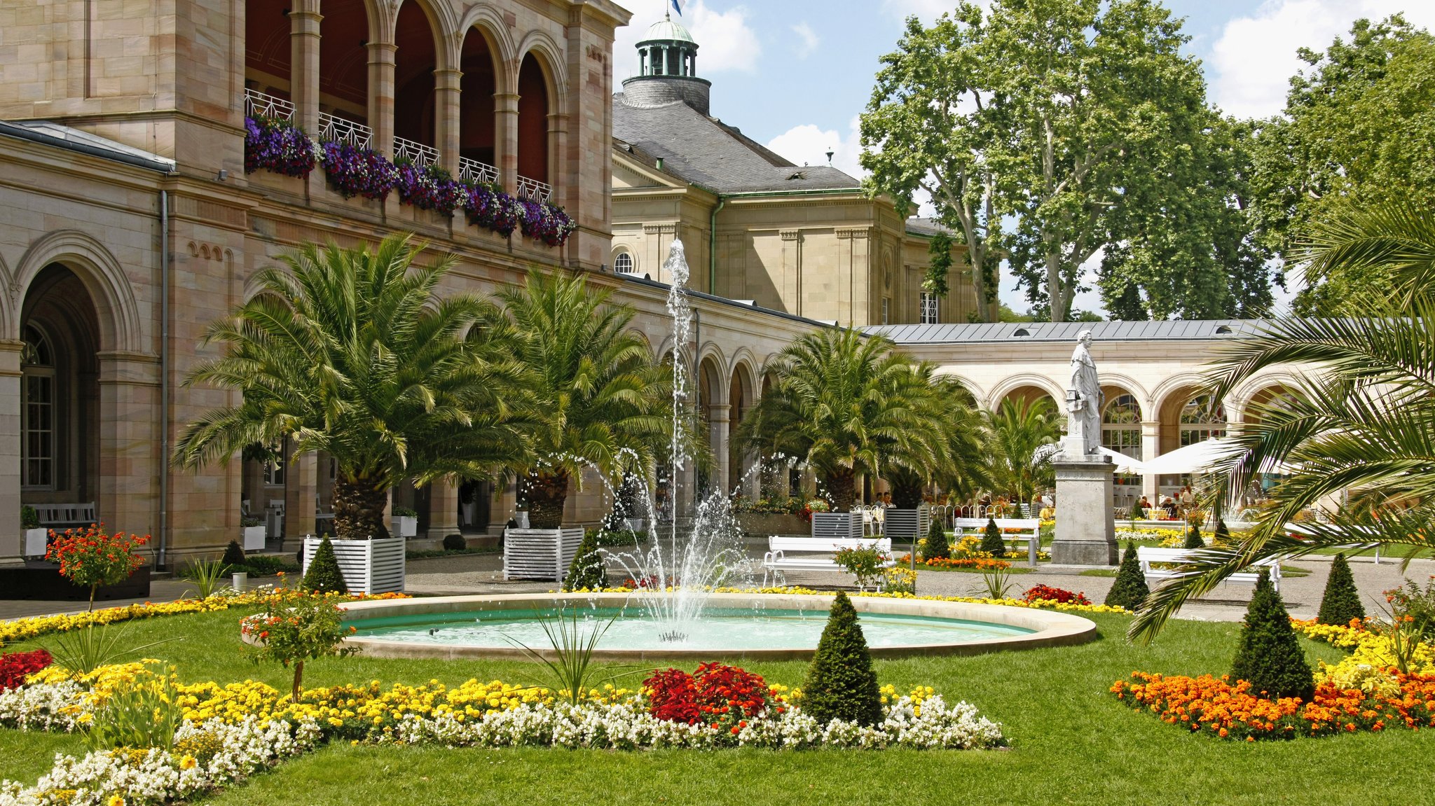 Kurpark in Bad Kissingen mit einem Brunnen, Palmen und Blumen