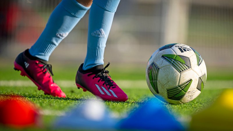 Eine Sportlerin mit Fußball und Adidas-Schuhen (Symbolbild). | Bild: dpa/picture alliance Eine Sportlerin mit Fußball und Adidas-Schuhen (Symbolbild).
