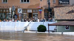 Menschen schauen sich in der Regensburger Altstadt am Donauufer hinter einer Schutzwand das Hochwasser an. | Bild:dpa-Bildfunk/Sven Hoppe