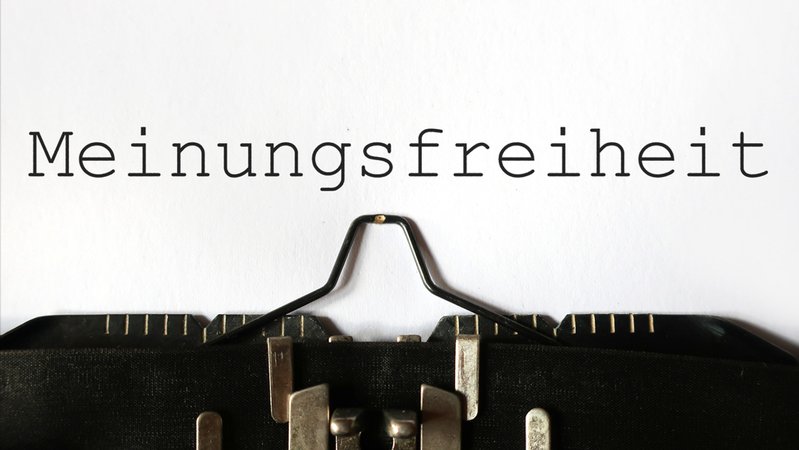 Auf einem in einer Schreibmaschine eingelegten Blatt Papier steht das Wort "Meinungsfreiheit" (Symbolbild) | Bild: stock.adobe.com/Pixi Auf einem in einer Schreibmaschine eingelegten Blatt Papier steht das Wort "Meinungsfreiheit" (Symbolbild)