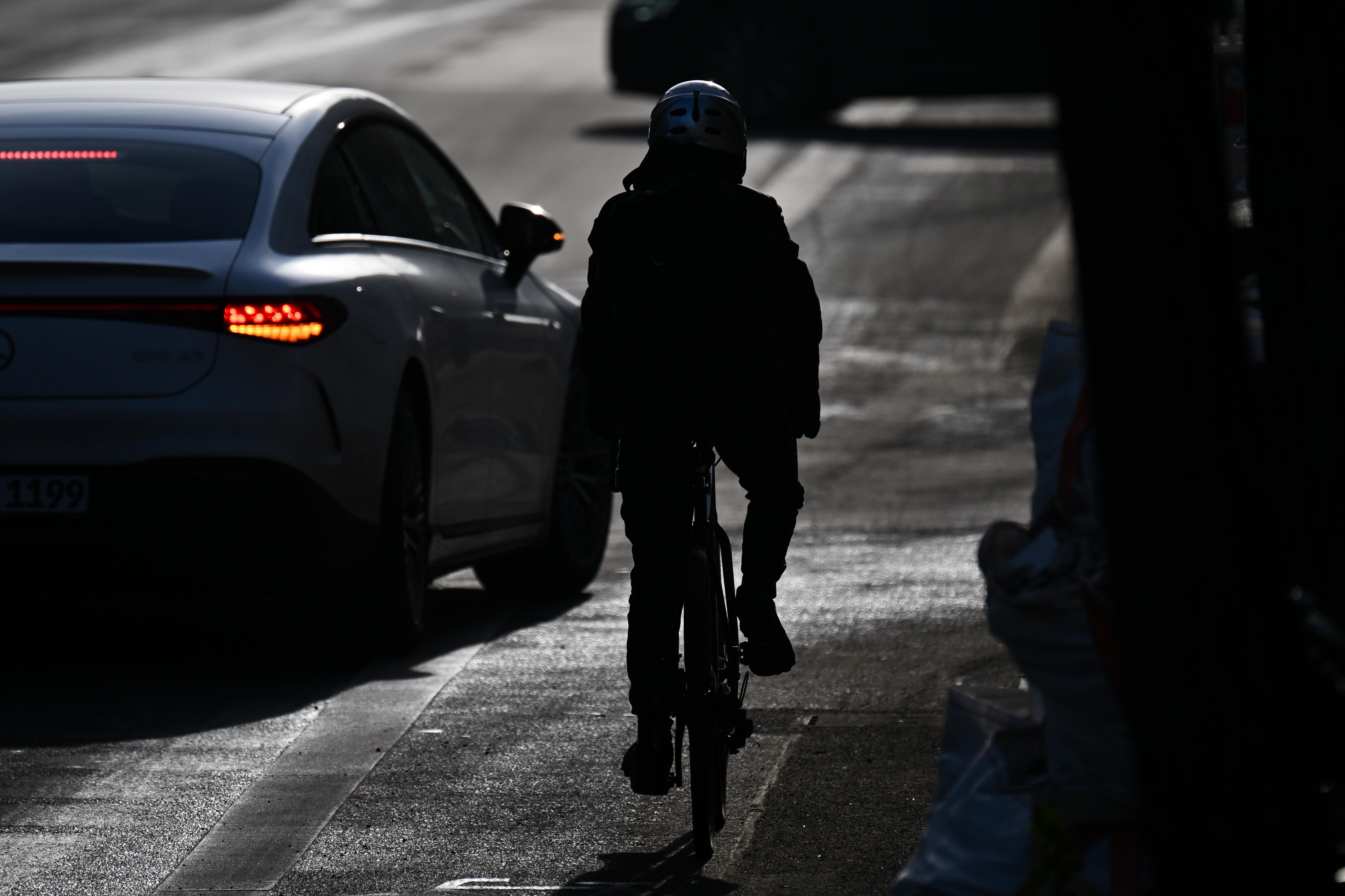 Fahrradfahrer in der Dämmerung von hinten auf der verschneiten Straße