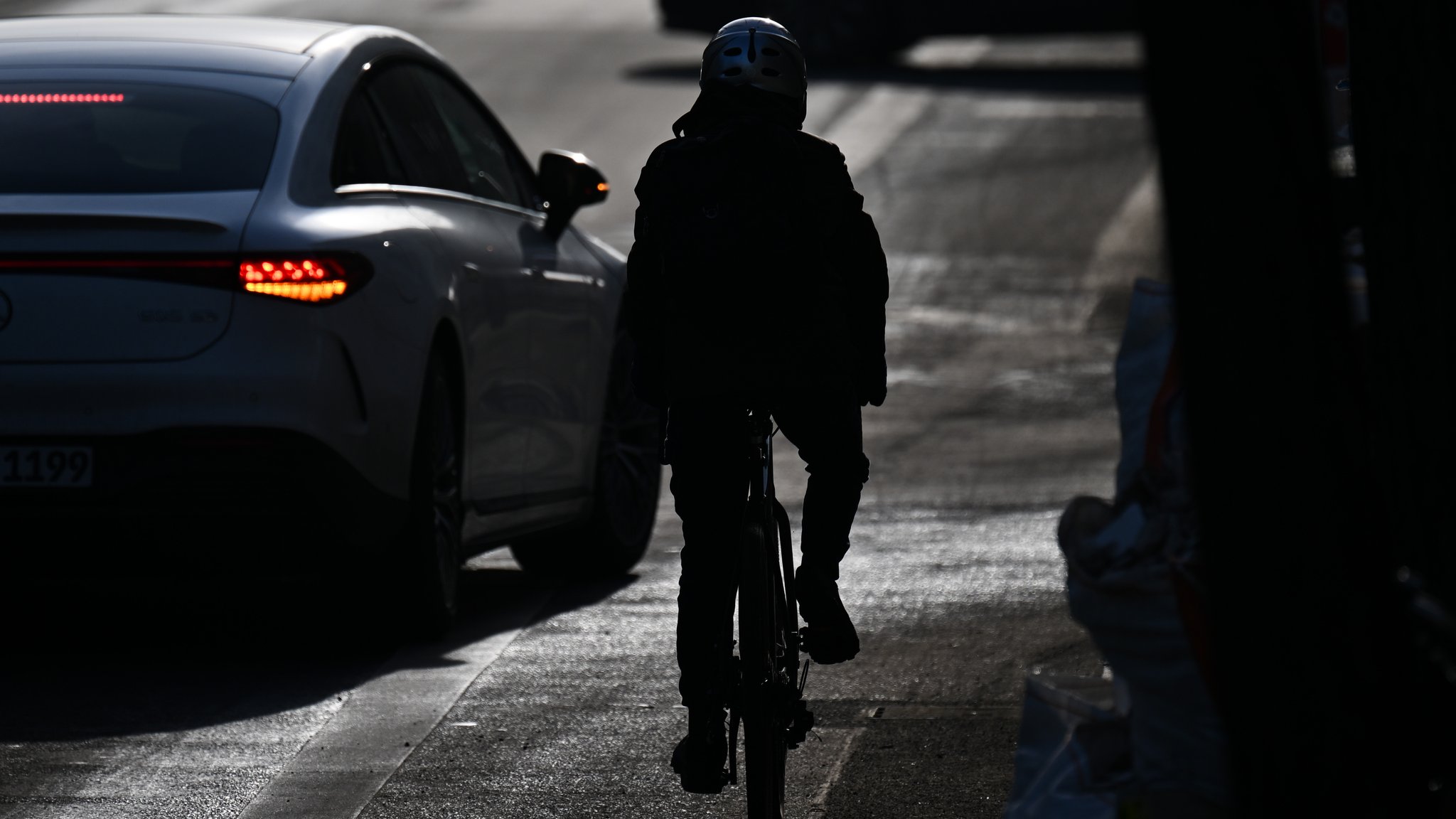 Fahrradfahrer in der Dämmerung von hinten auf der verschneiten Straße