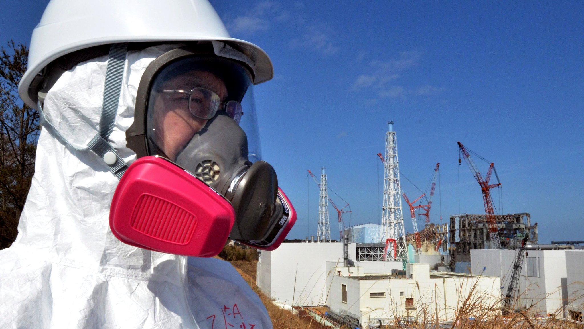 Besucher mit Atemmaske vor dem Kraftwerk Fukushima