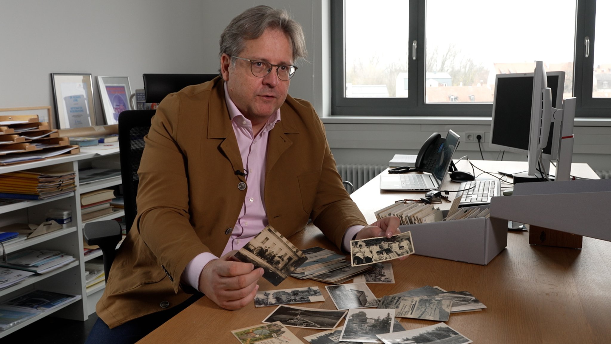 Richard Loibl, Direktor des Hauses der Bayerischen Geschichte, hält alte Postkarten in der Hand.
