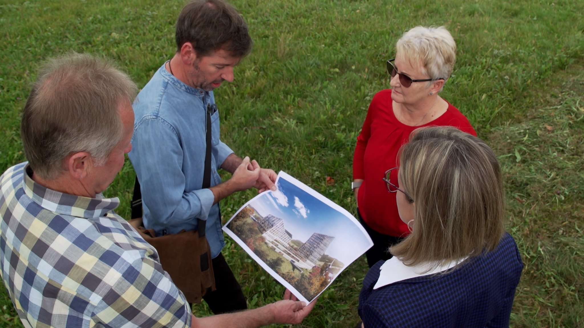 Tobias Waltner (zweiter von links), Benedikt Berger, Sandra Ammer (rechts) und Sylvia Ammer (Mitte)  von der Bürgerinitiative gegen das Hotel halten einen Plan in der Hand, auf dem das geplante Hotel zu sehen ist