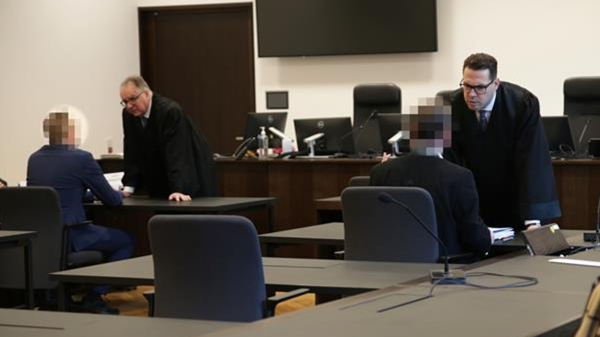 Zwei Angeklagte mit ihren Verteidigern in einem Gerichtssaal.