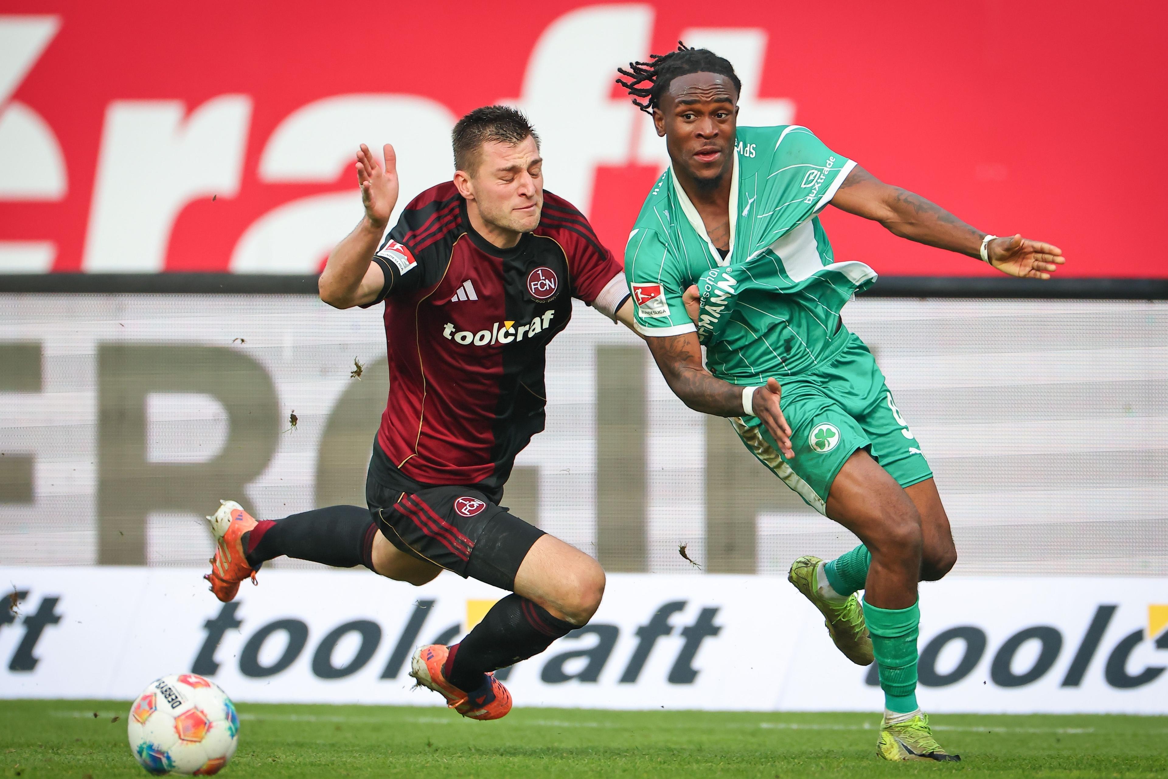 07.12.2025, Bayern, Nürnberg: Fußball: 2. Bundesliga, 1. FC Nürnberg - SpVgg Greuther Fürth, 15. Spieltag im Max-Morlock-Stadion. Robin Knoche (l, 1. FC Nürnberg) und Noel Futkeu (SpVgg Greuther Fürth) kämpfen um den Ball. Foto: Daniel Karmann/dpa - WICHTIGER HINWEIS: Gemäß den Vorgaben der DFL Deutsche Fußball Liga bzw. des DFB Deutscher Fußball-Bund ist es untersagt, in dem Stadion und/oder vom Spiel angefertigte Fotoaufnahmen in Form von Sequenzbildern und/oder videoähnlichen Fotostrecken zu verwerten bzw. verwerten zu lassen. +++ dpa-Bildfunk +++