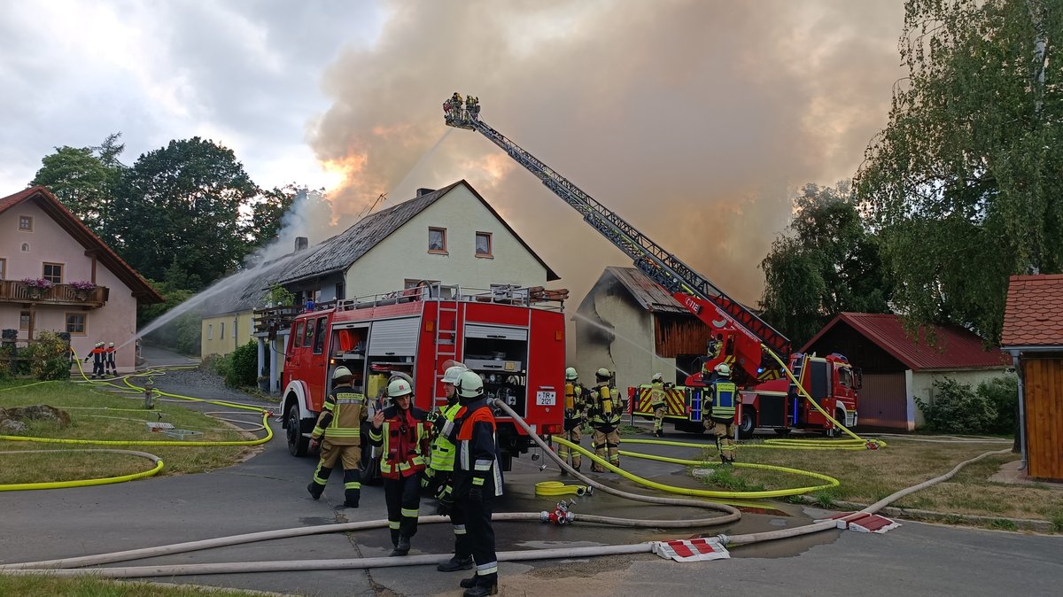 Feuerwehr bei Löscharbeiten auf dem brennenden Bauernhof in Lauterbach bei Mähring. Im Hintergrund qualmt es stark.