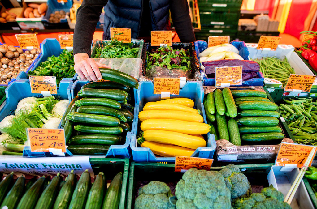 Ein Verkäufer greift an einem Obst- und Gemüsestand auf dem Wochenmarkt in eine Kiste mit Zucchini. Das Leben in Deutschland hat sich in den vergangenen Monaten spürbar verteuert. So hoch war die Inflationsrate seit Jahrzehnten nicht mehr.
