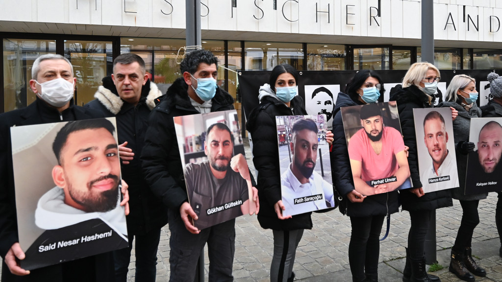 Angehörige der Opfer des rassistischen Anschlags von Hanau 2020 halten bei einer Mahnwache vor dem hessischen Landtag Fotos der Opfer. 