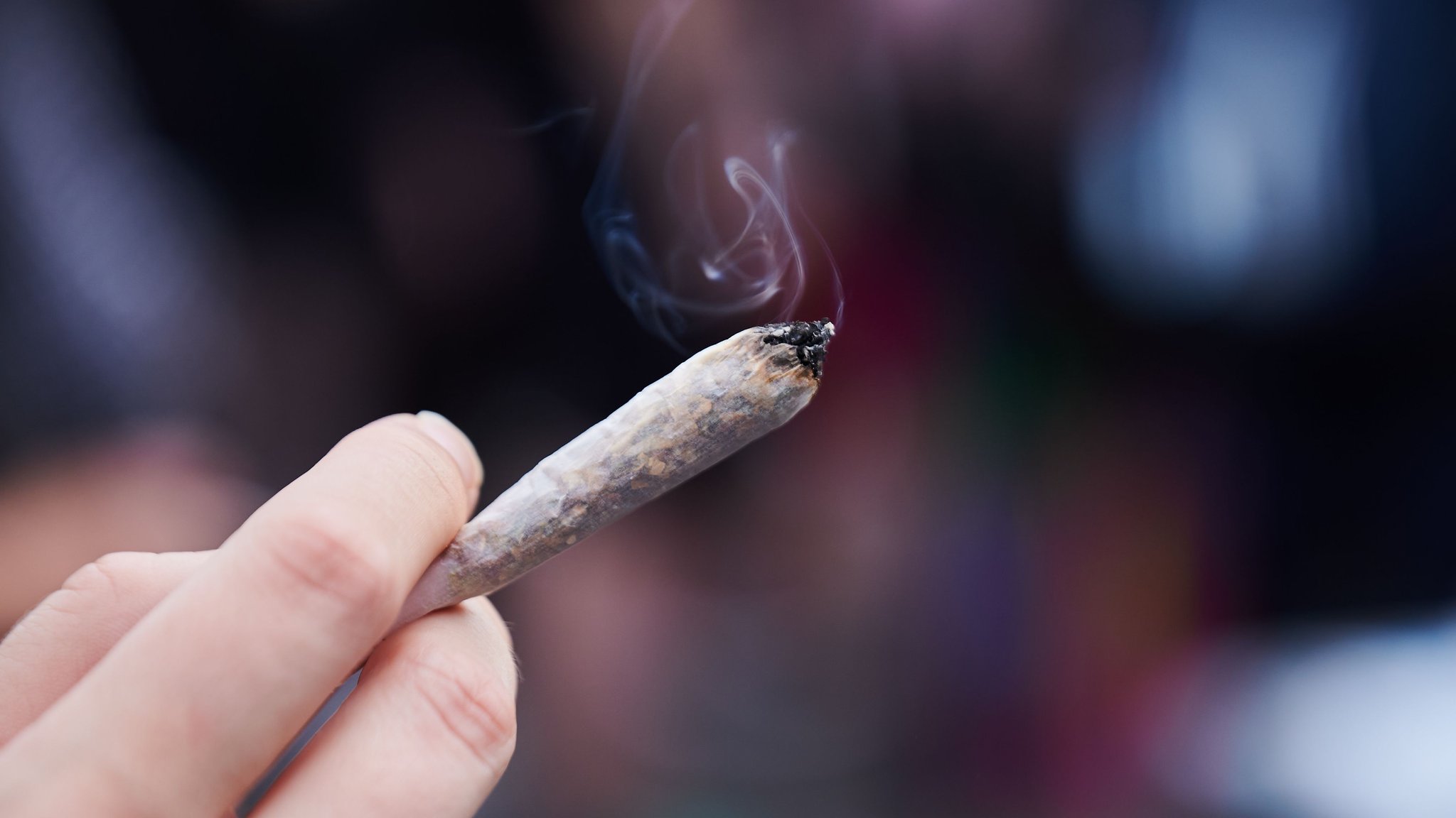 Eine Frau hält einen Joint in der Hand.
