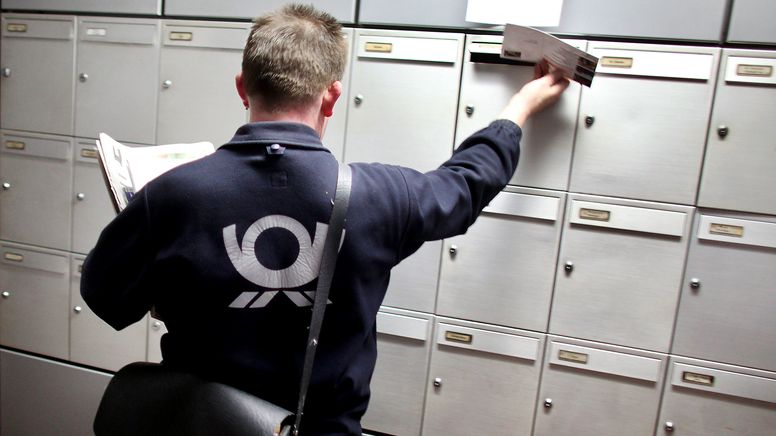 Ein Postbote wirft Post in Briefkästen ein. | Bild:dpa-Bildfunk/Oliver Berg