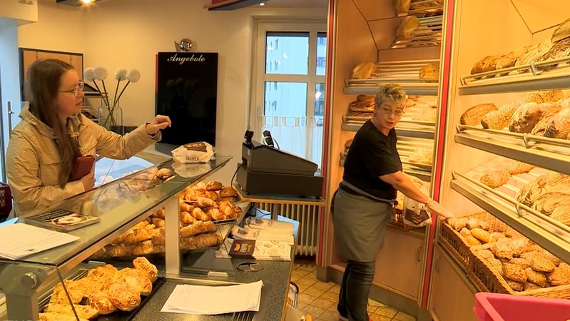 In einer Bäckerei bedient eine Verkäuferin am Verkaufstresen.