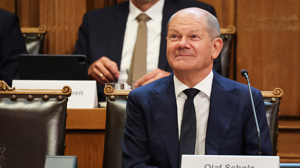 19.08.2022, Hamburg: Bundeskanzler Olaf Scholz (SPD) sitzt auf seinem Platz auf der Senatsbank mit einem Plastikschild mit dem Text ·Olaf Scholz Zeuge· vor Beginn einer Sitzung des Parlamentarischen Untersuchungsausschusses ·Cum-Ex· im Plenarsaal der Hamburgischen Bürgerschaft im Rathaus. Scholz sagt erneut vor dem Ausschuss aus.