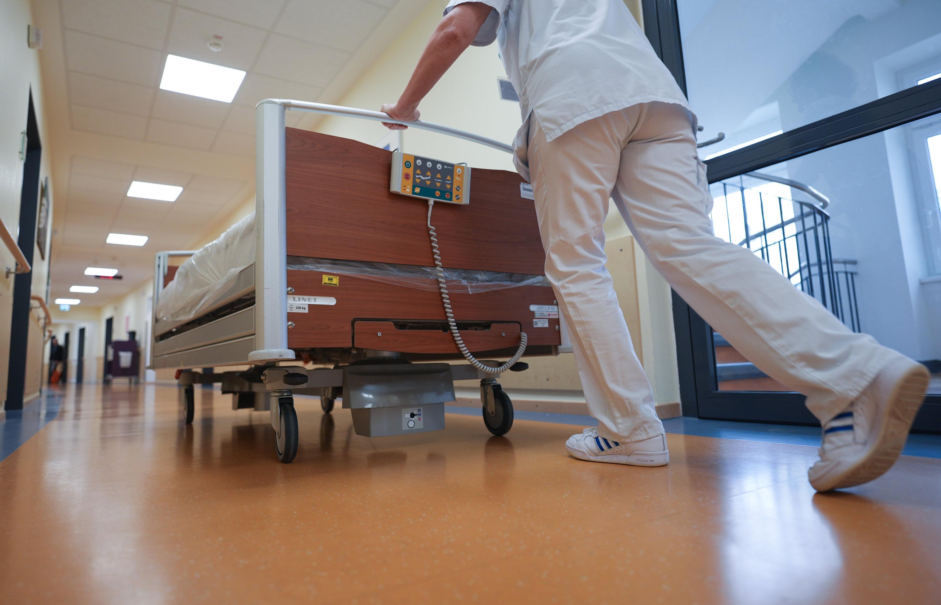 Eine Krankenschwester schiebt ein Bett über den Flur einer Krankenstation.