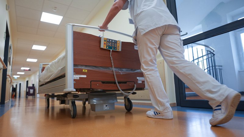 Eine Krankenschwester schiebt ein Bett über den Flur einer Krankenstation. | Bild: dpa-Bildfunk/Marcus Brandt Eine Krankenschwester schiebt ein Bett über den Flur einer Krankenstation.