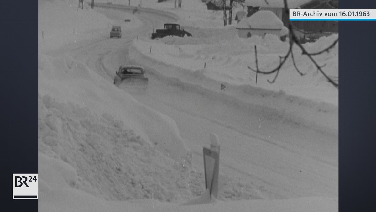 Schneebedeckte Straße mit Autos und hohem Schnee am Straßenrand