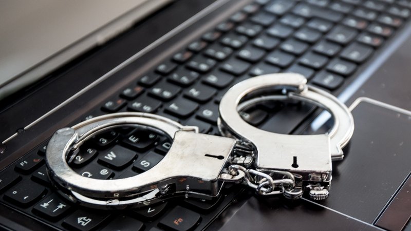 Handschellen auf einer Computertastatur. | Bild: picture alliance / Fotostand | Fotostand / Schmitt Handschellen auf einer Computertastatur.