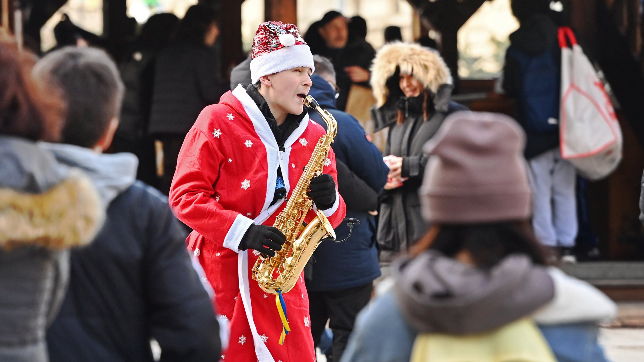 Strassenmusikant als Weihnachtsmann verkleidet spielt Saxophon.