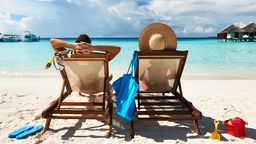Symbolbild: Ein Pärchen in Liegestühlen am Strand und schaut auf türkisblaues Meer. In Griechenland werden Strandliegen nun beschränkt.  | Bild:BR-Bil/Adobe/Haveseen