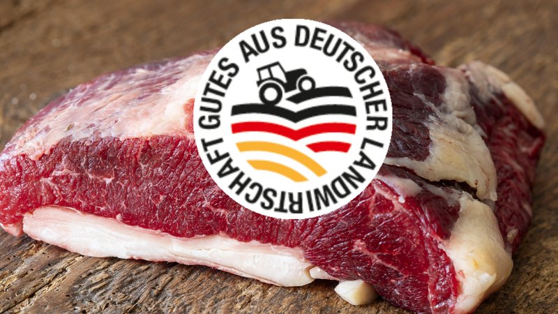 Ein Stück Fleisch über dem das Logo des Herkunftskennzeichen Deutschland prangert, ein schwarzer Traktor der über einen schwarz-rot-goldenen Acker fährt. Drum herum steht "Gutes aus Deutscher Landwirtschaft"