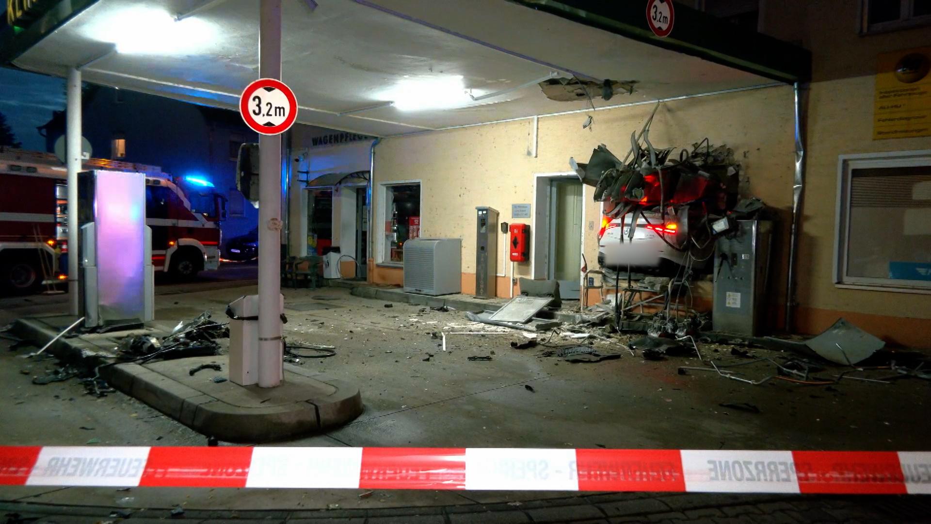 Die zerstörte Tanksstelle mit Absperrband und Auto in der Wand