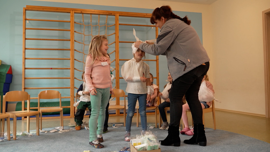 Wie man anderen hilft, kann man gar nicht früh genug lernen. Im Kindergarten von Kürn im Landkreis Regensburg gibt es deshalb Erste-Hilfe-Kurse schon für die Kleinsten. Notruf absetzen, Verband anlegen - alles kein Problem! | Bild: BR Wie man anderen hilft, kann man gar nicht früh genug lernen. Im Kindergarten von Kürn im Landkreis Regensburg gibt es deshalb Erste-Hilfe-Kurse schon für die Kleinsten. Notruf absetzen, Verband anlegen - alles kein Problem!