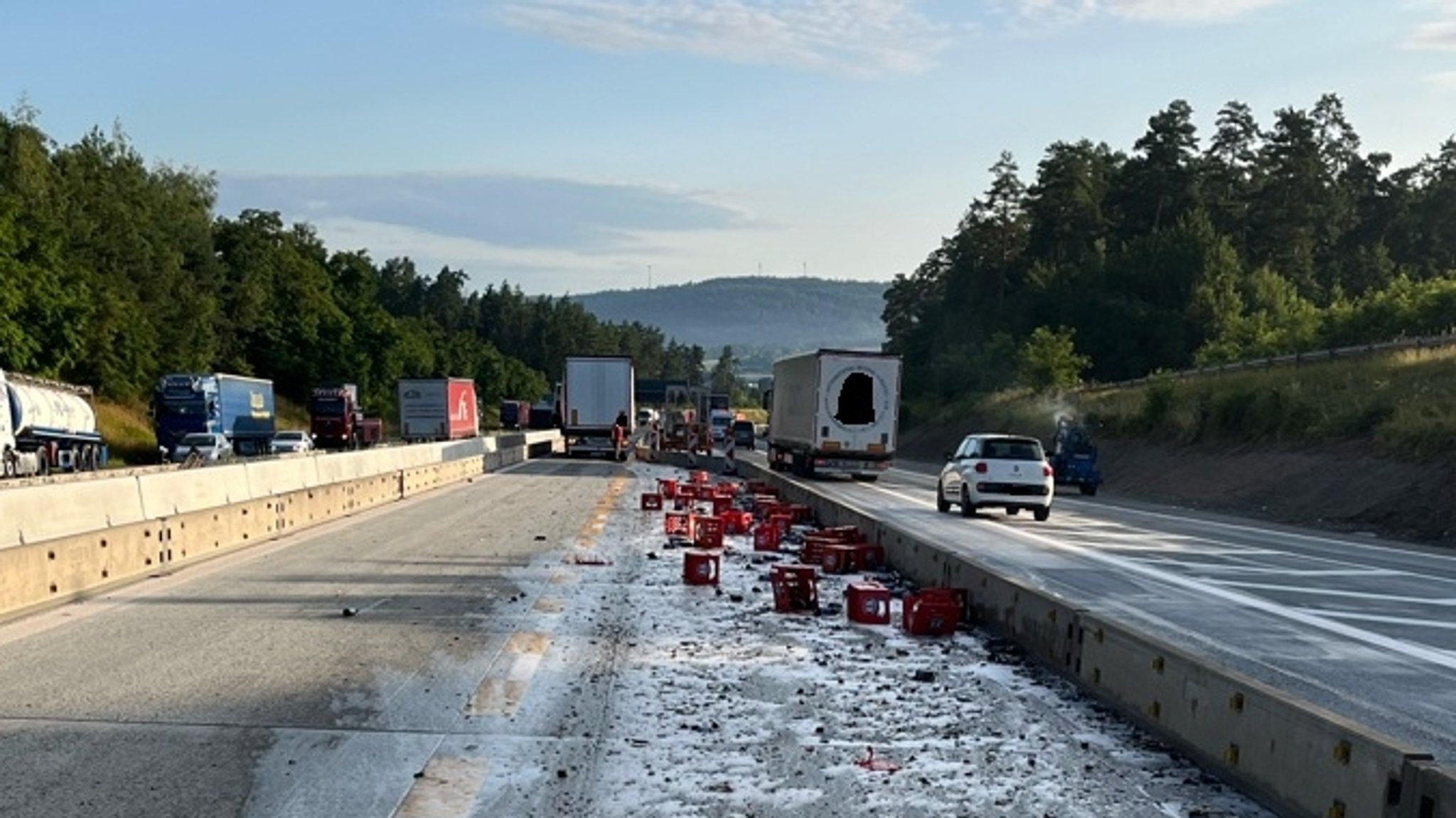 Die Unfallstelle auf der A9 nahe Bad Berneck. Zu sehen sind mehrere Kisten Bier, die auf der Autobahn liegen. Im Vordergrund sind Lkw und Autos zu sehen. 