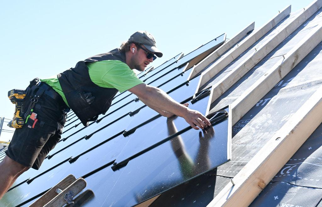 Ein Handwerker installiert eine Photovoltaik auf einem Dach.