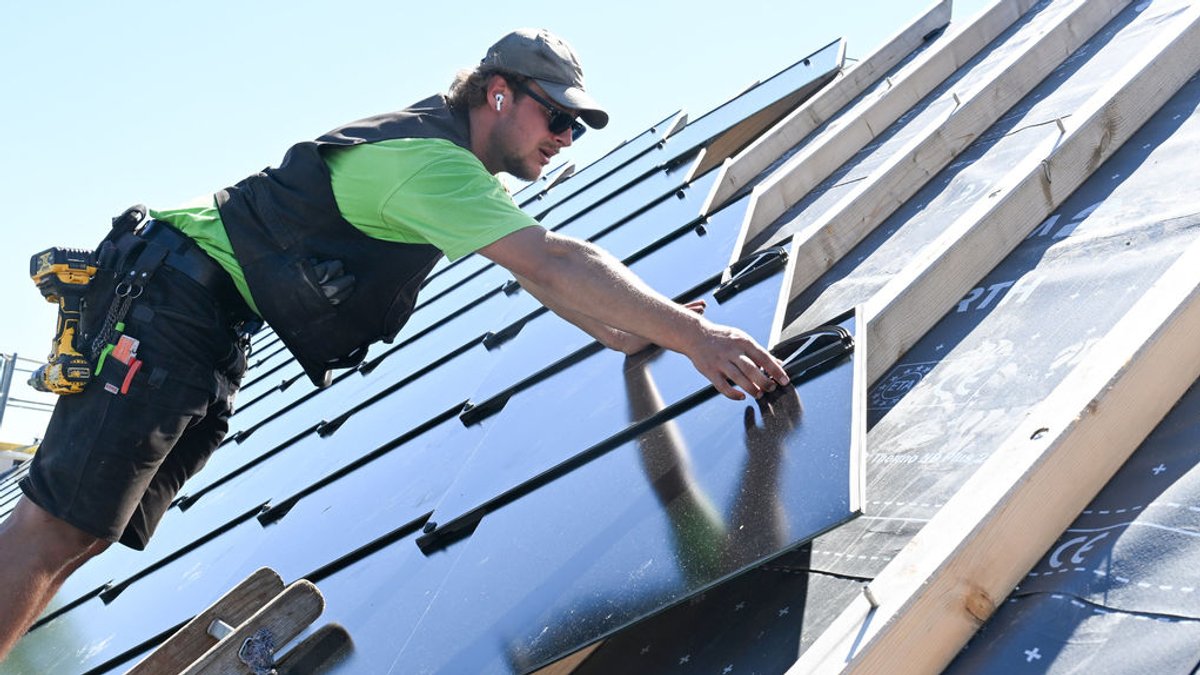Ein Handwerker installiert eine Photovoltaik auf einem Dach.