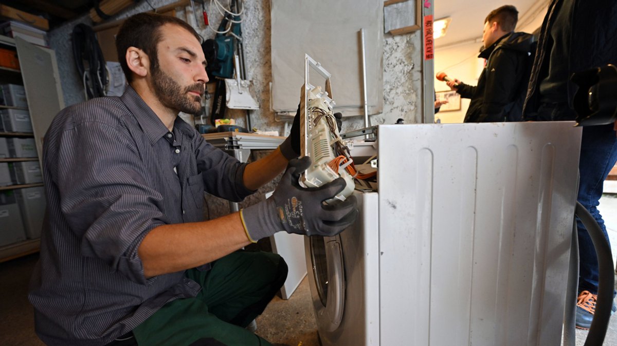Thüringen, Erfurt: Sebastian Stock repariert eine defekte Waschmaschine in der Werkstatt der Erfurter Reparatur-Initiative BSR.