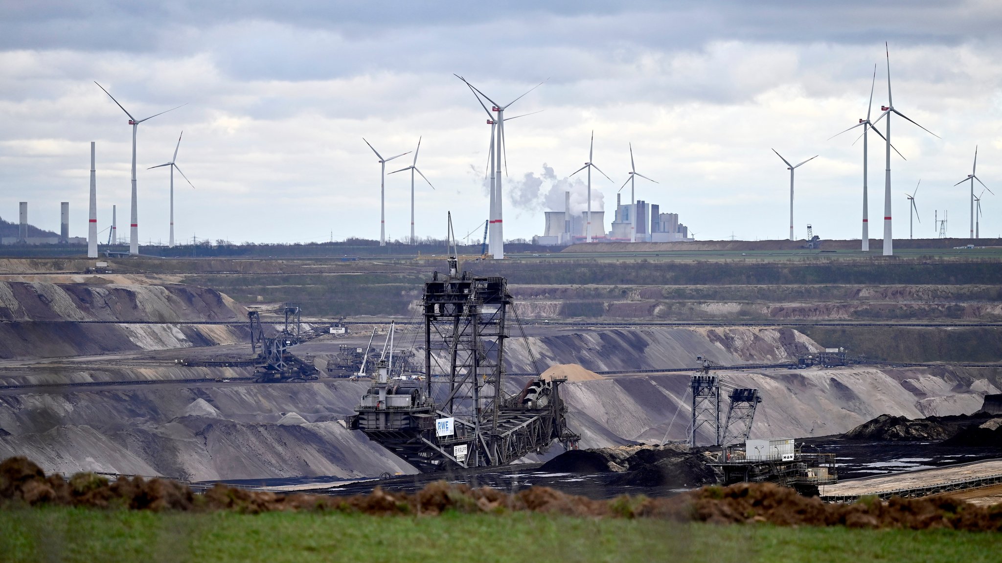 Windkraftanlagen stehen auf einem Feld bei Erkelenz nahe des Braunkohletagebau Garzweiler II, dahinter das Kohlekraftwerk Neurath von RWE. 