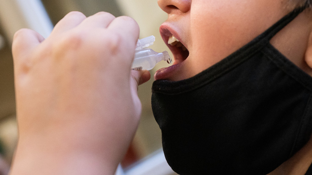 Ein Schüler tropft eine medizinisch Flüssigkeit in seinen Mund.