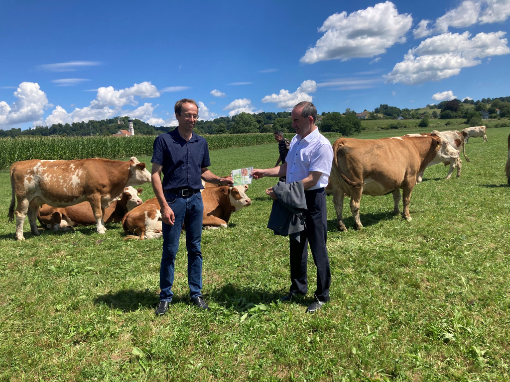 Wirtschaftsminister Aiwanger überreicht 130 Euro an Landwirt Georg Schweiger in Pähl, damit dieser sein Bußgeld wegen Kuhfladen bezahlen kann.