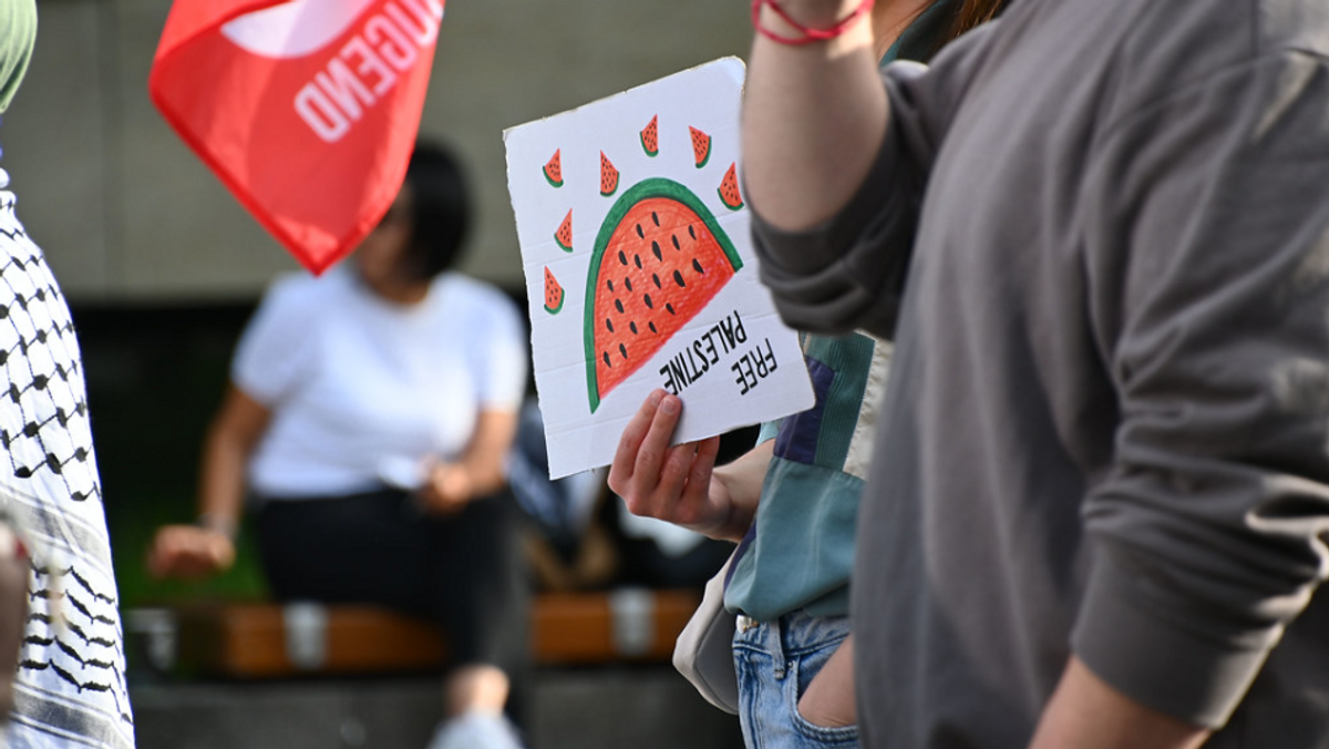Eine Demonstrantin hält ein Schild in der Hand, auf dem eine Wassermelone und