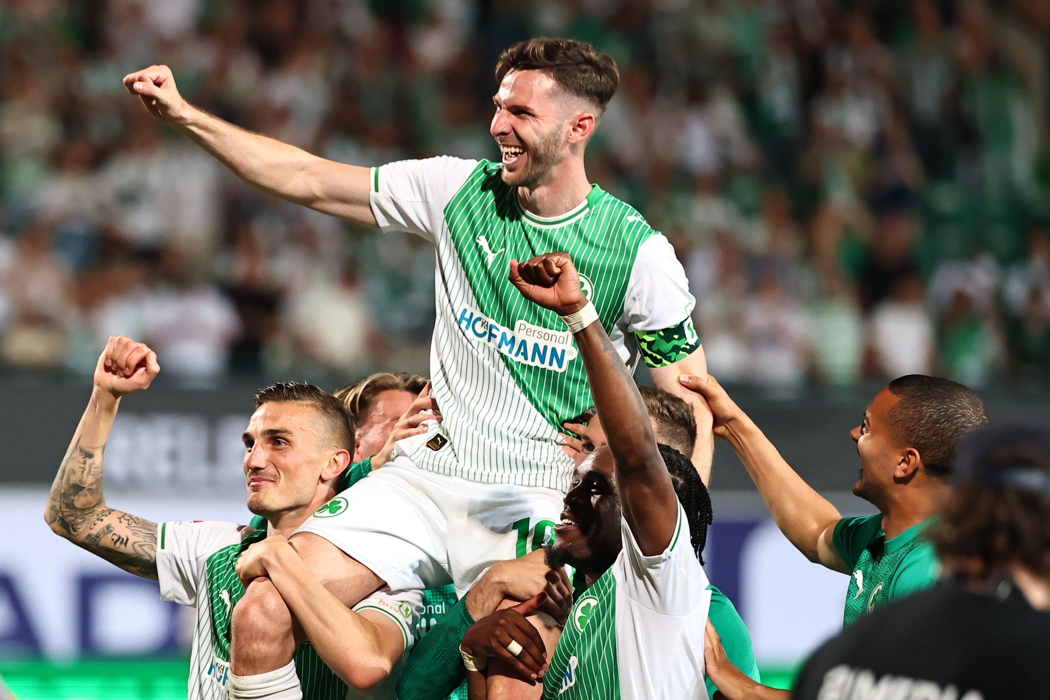 26.05.2026, Bayern, Fürth: Fußball, Männer: 2. Bundesliga - Relegation, SpVgg Greuther Fürth - Rot-Weiss Essen, Philipp Ziereis (SpVgg Greuther Fürth), Branimir Hrgota (SpVgg Greuther Fürth) und Noel Futkeu (SpVgg Greuther Fürth) (l-r) feiern nach der Partie. Foto: Daniel Karmann/dpa - WICHTIGER HINWEIS: Gemäß den Vorgaben der DFL Deutsche Fußball Liga bzw. des DFB Deutscher Fußball-Bund ist es untersagt, in dem Stadion und/oder vom Spiel angefertigte Fotoaufnahmen in Form von Sequenzbildern und/oder videoähnlichen Fotostrecken zu verwerten bzw. verwerten zu lassen. +++ dpa-Bildfunk +++